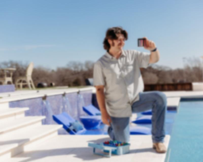Man looking at his tool that measure pool water quality next to a pool.