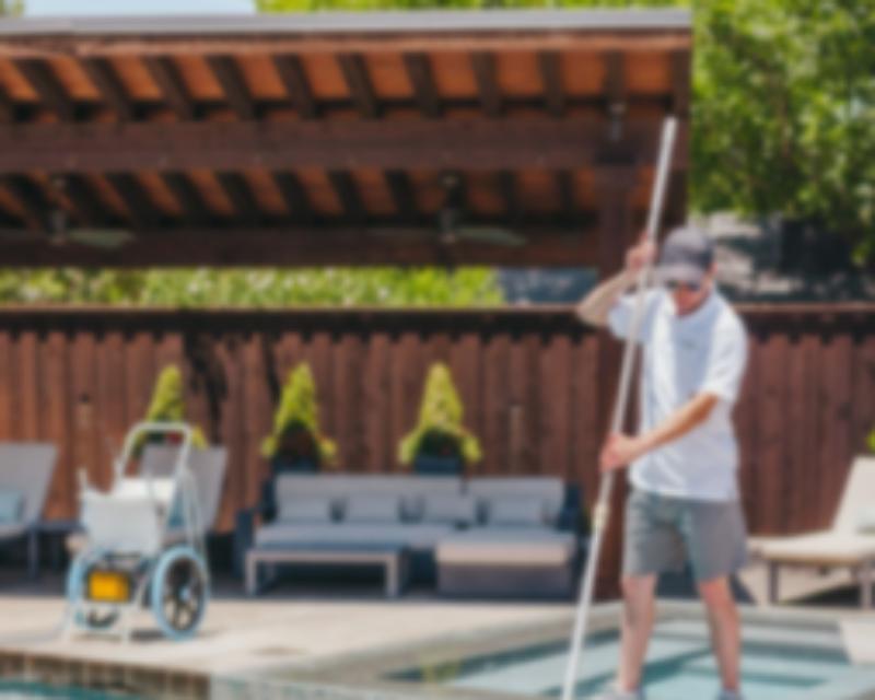 Pool cleaning and maintenance worker cleaning pool.